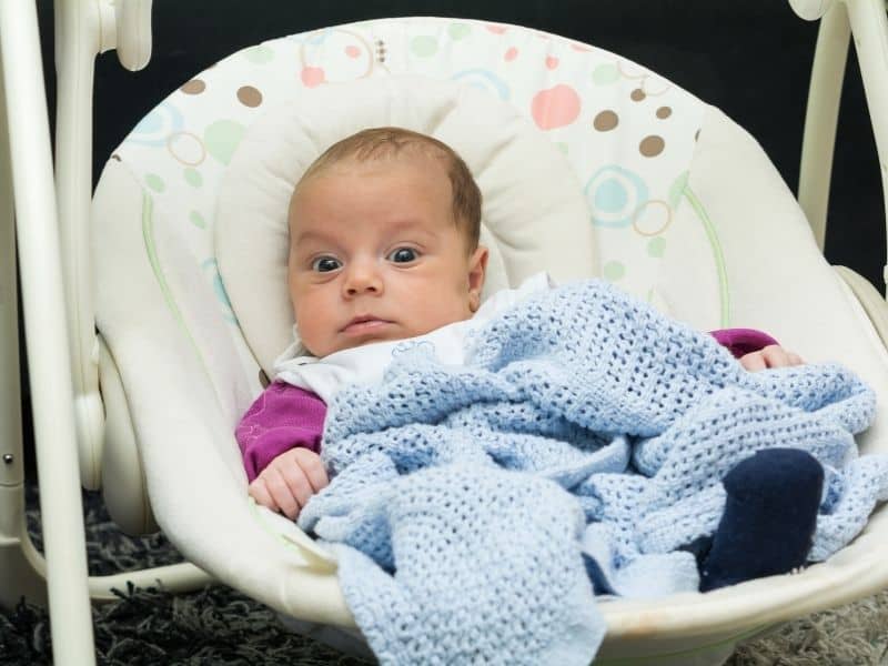 baby on a baby swing looking at camera