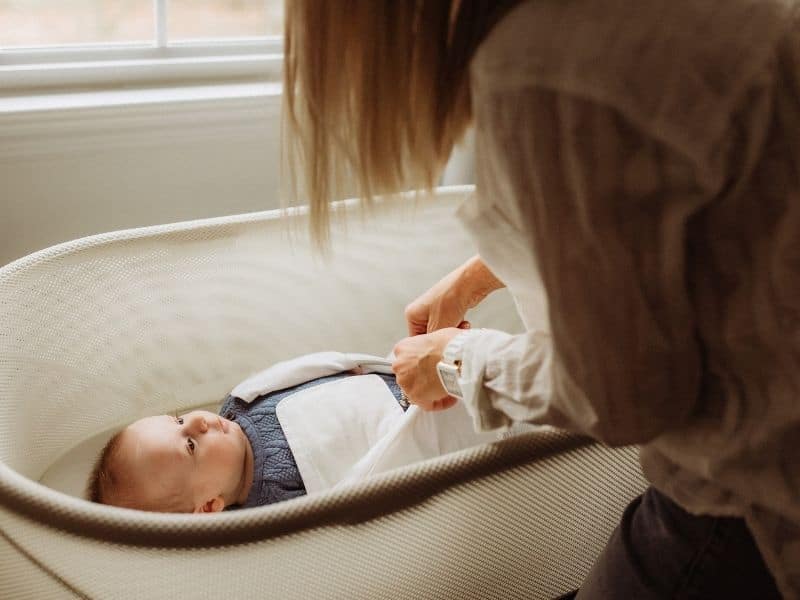 baby inside a bassinet and mommy